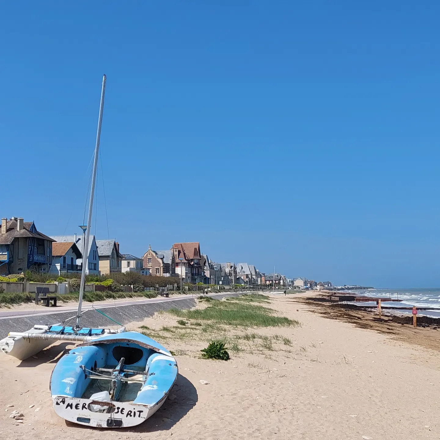 Deux petits voiliers sont en haut de la plage devant des maisons