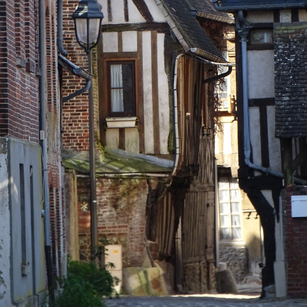 Une petite ruelle entre de vieux batiments à colombages et en brique rouge à Orbec